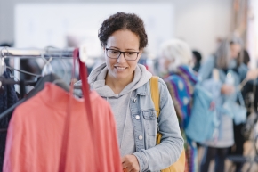 ABZ*AUSTRIA Businesskleidermarkt, Frau hält sich einen Rock probeweise vor den Körper.